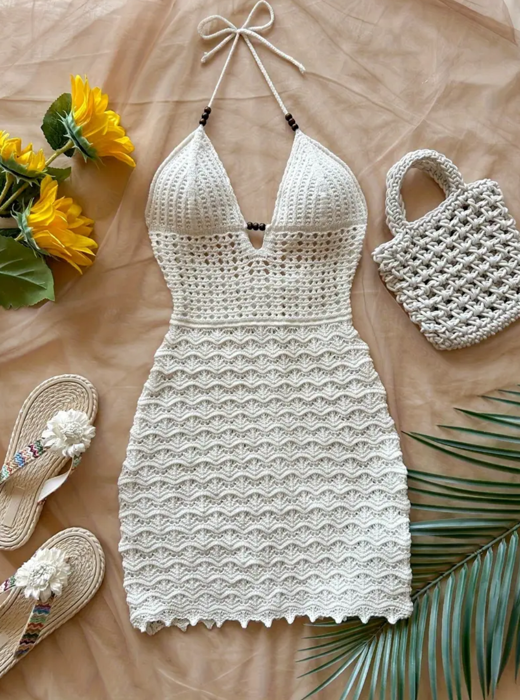 White crochet dress with yellow flowers and a handbag on a brown surface