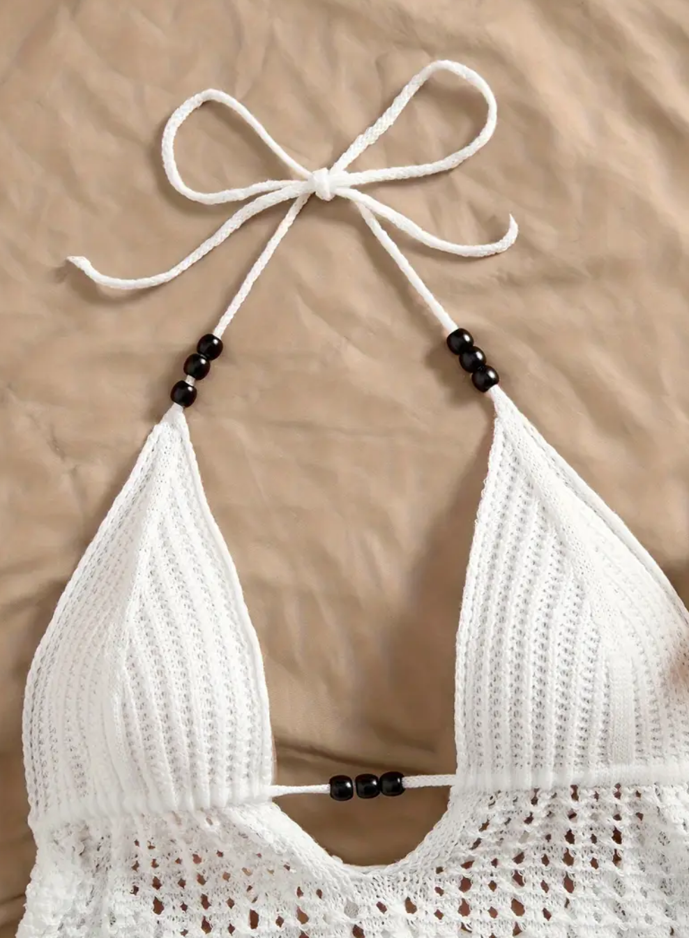 White crochet bikini top with beads on a beige background