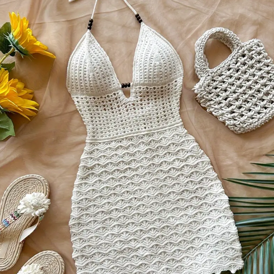 White crochet dress on a wooden surface with flowers and sandals